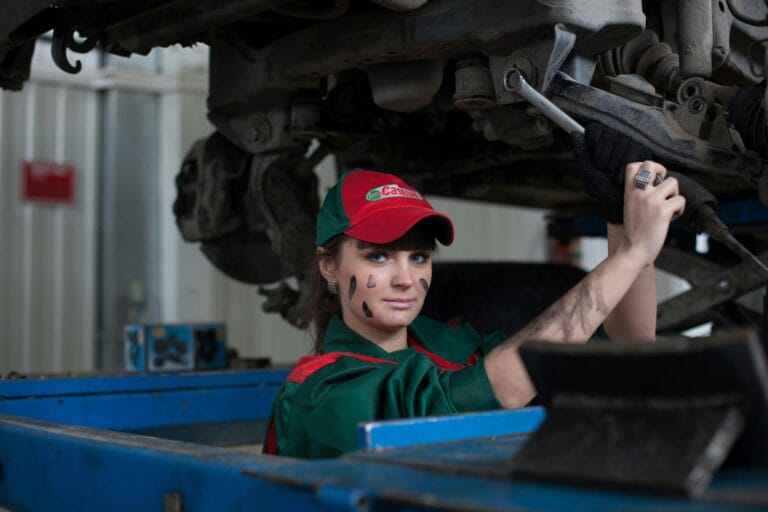 Mujer mecánica realizando el mantenimiento de un coche en un taller de reparación de automóviles, mostrando habilidad y concentración.